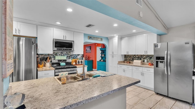 kitchen with visible vents, white cabinetry, stainless steel appliances, and a sink