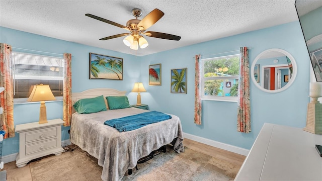 bedroom with a textured ceiling, ceiling fan, and baseboards