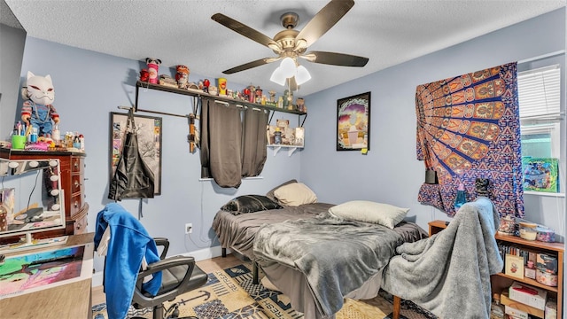 bedroom with ceiling fan, a textured ceiling, and wood finished floors