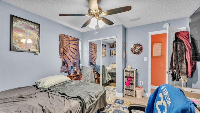 bedroom with baseboards, visible vents, ceiling fan, a textured ceiling, and a closet