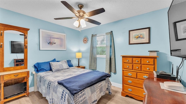 bedroom with a textured ceiling, ceiling fan, light wood-style flooring, and baseboards