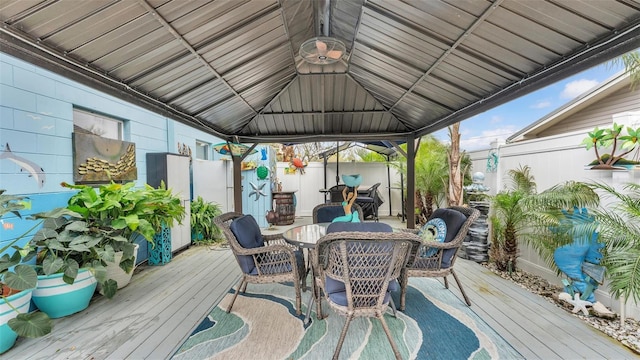 wooden deck featuring outdoor dining space, fence, and a gazebo