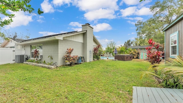 view of property exterior featuring roof mounted solar panels, a lawn, a hot tub, and central air condition unit