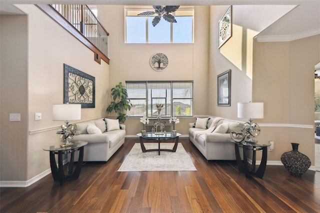 living area featuring a high ceiling, dark wood finished floors, and baseboards