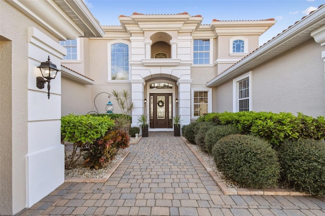 doorway to property with a tile roof and stucco siding