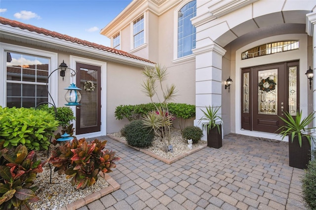 property entrance featuring a tiled roof and stucco siding