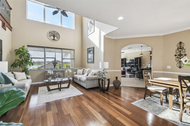 living room featuring arched walkways, crown molding, baseboards, and wood finished floors