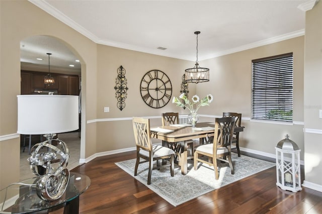 dining area featuring crown molding, dark wood-type flooring, arched walkways, and baseboards