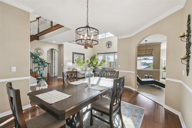 dining area featuring arched walkways, a notable chandelier, baseboards, wood-type flooring, and crown molding