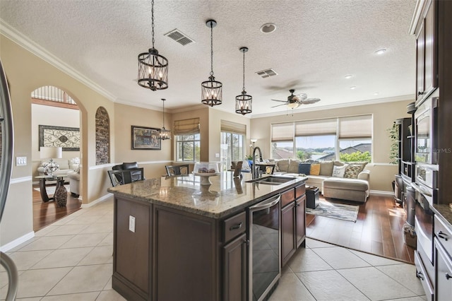 kitchen with open floor plan, beverage cooler, a sink, and visible vents