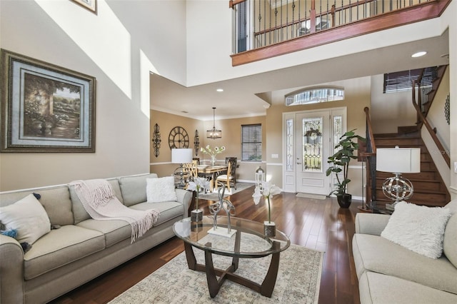 living area featuring baseboards, a towering ceiling, stairway, wood finished floors, and recessed lighting