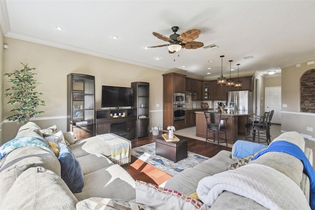 living area featuring crown molding, visible vents, and wood finished floors