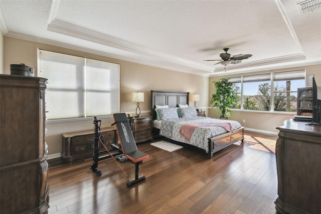 bedroom with dark wood finished floors, ornamental molding, a raised ceiling, and visible vents