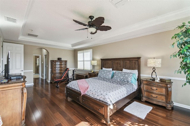 bedroom featuring visible vents, a tray ceiling, arched walkways, and wood finished floors