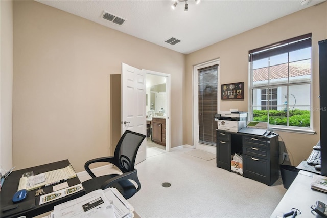 home office featuring light carpet, baseboards, visible vents, and a textured ceiling