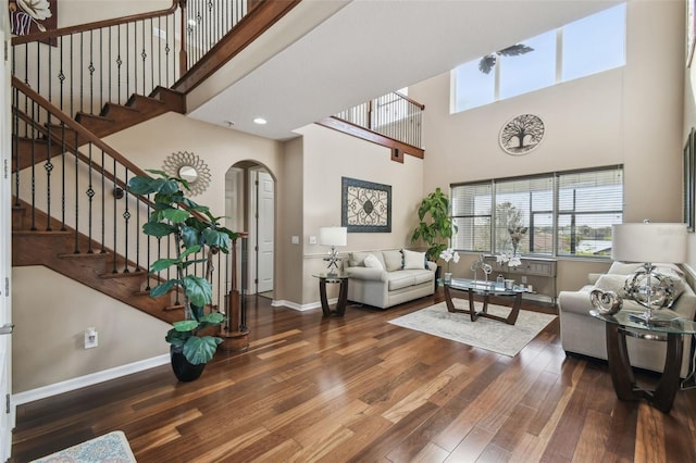 living area with a wealth of natural light, arched walkways, baseboards, and wood finished floors