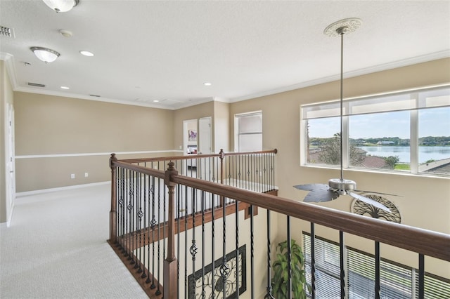 hall with visible vents, baseboards, a water view, carpet, and crown molding