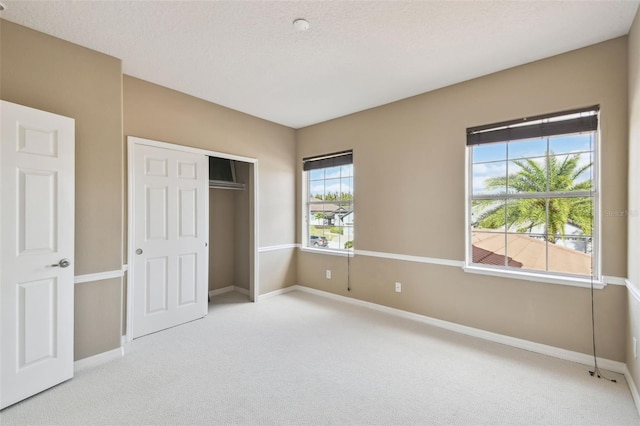 unfurnished bedroom with a closet, a textured ceiling, baseboards, and carpet flooring