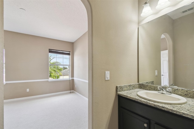 bathroom with visible vents, vanity, baseboards, and a textured ceiling