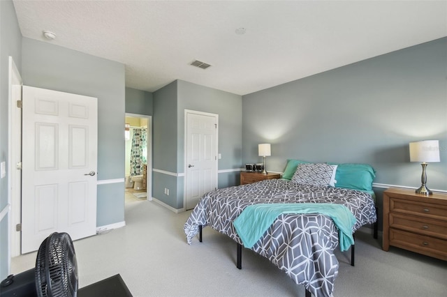 bedroom with carpet floors, visible vents, ensuite bath, and baseboards