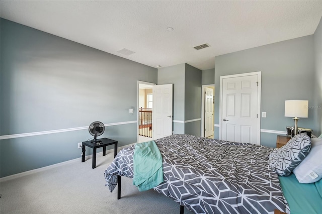 carpeted bedroom featuring a textured ceiling, visible vents, and baseboards