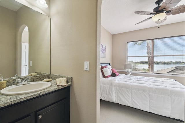 bedroom featuring arched walkways, a sink, and a ceiling fan