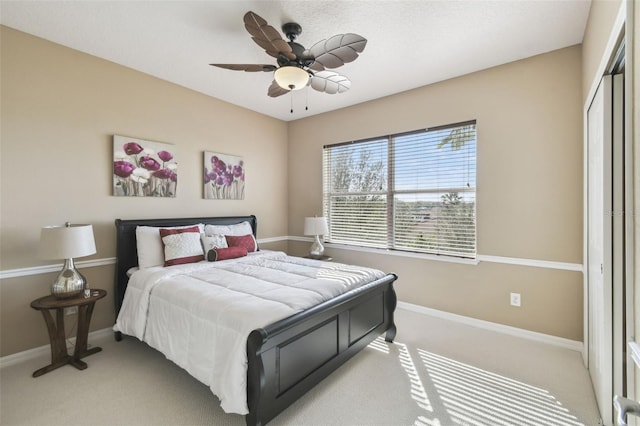 bedroom with light carpet, ceiling fan, baseboards, and a closet