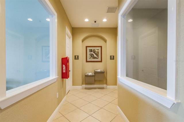 hallway with recessed lighting, visible vents, baseboards, and light tile patterned flooring