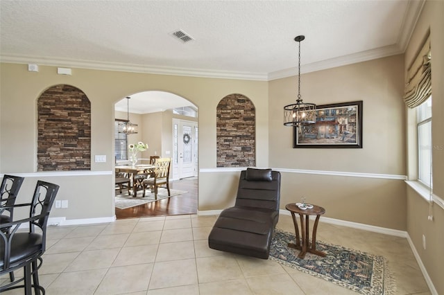 sitting room with arched walkways, light tile patterned floors, visible vents, ornamental molding, and a chandelier