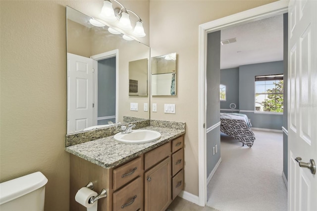 bathroom featuring toilet, vanity, visible vents, and baseboards