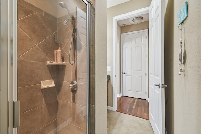 bathroom featuring tile patterned flooring, a shower stall, and baseboards