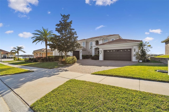 mediterranean / spanish-style house with a garage, a front yard, decorative driveway, and a tile roof