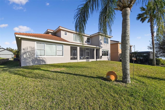 rear view of property with a sunroom, a yard, a tiled roof, and stucco siding