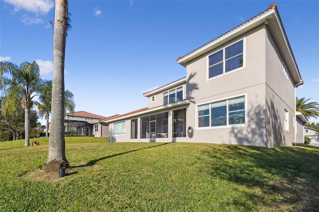 rear view of property with stucco siding, a sunroom, and a yard