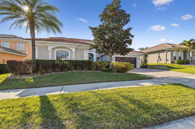 mediterranean / spanish house with a tiled roof, an attached garage, decorative driveway, a front yard, and stucco siding