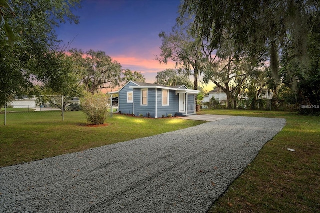 view of front facade with driveway, a front lawn, and fence