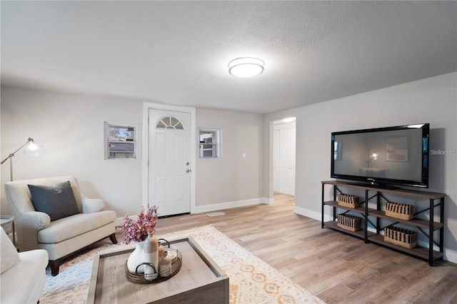 living area with light wood finished floors, a textured ceiling, and baseboards