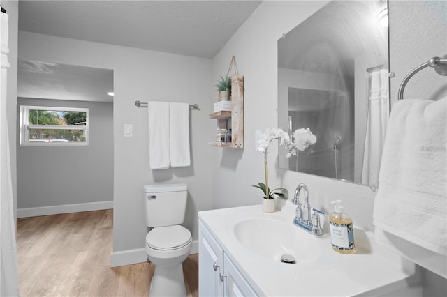 full bath featuring toilet, a textured ceiling, wood finished floors, baseboards, and vanity