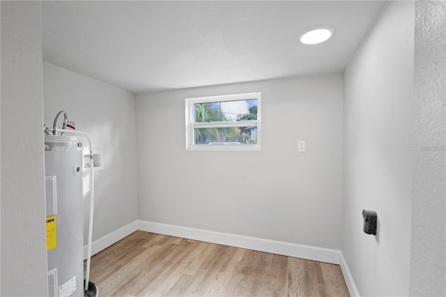 clothes washing area featuring electric water heater, baseboards, washer hookup, laundry area, and light wood-style floors