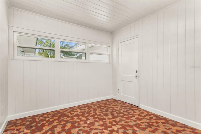 unfurnished room with wood ceiling and baseboards