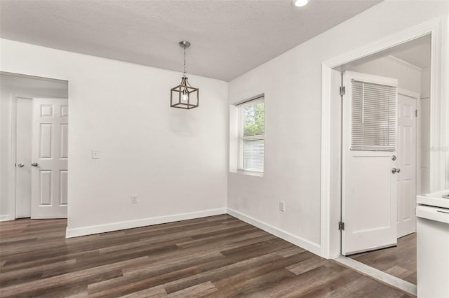 unfurnished dining area featuring a textured ceiling, baseboards, and wood finished floors