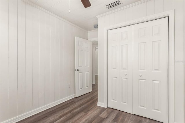 unfurnished bedroom with ceiling fan, visible vents, a closet, dark wood finished floors, and crown molding