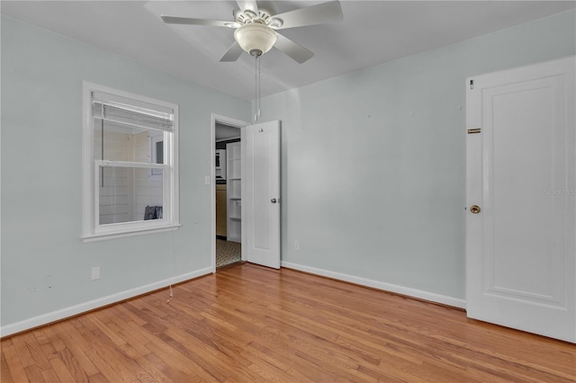 unfurnished room with ceiling fan, wood finished floors, and baseboards