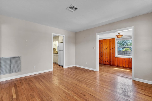 empty room with light wood-style flooring, visible vents, and baseboards