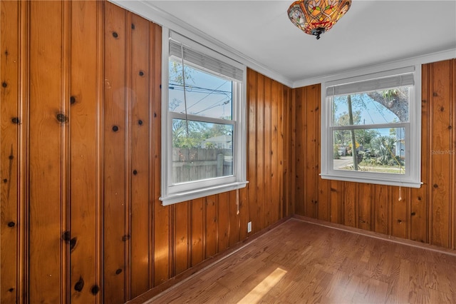 unfurnished room with wood walls, baseboards, and wood finished floors