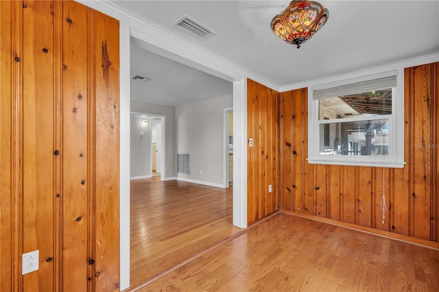 spare room with baseboards, visible vents, and wood finished floors