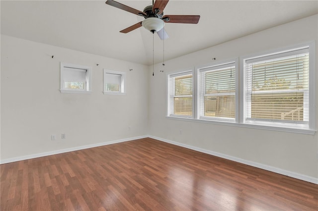 empty room with lofted ceiling, ceiling fan, wood finished floors, and baseboards