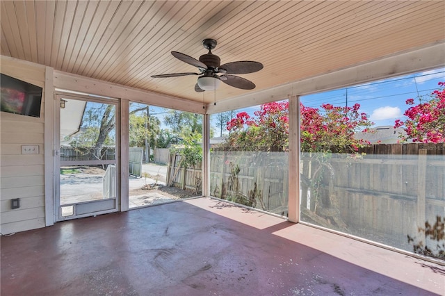 unfurnished sunroom featuring wood ceiling and a ceiling fan