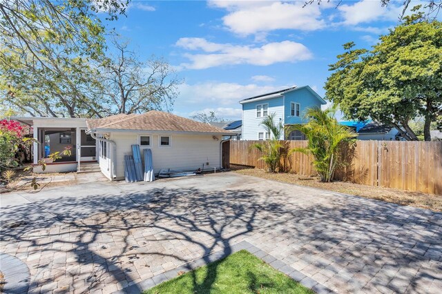 rear view of house with decorative driveway and fence