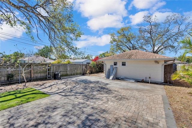 back of house with a shingled roof, fence private yard, and a patio area